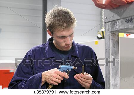 Stock Image - Male engineer making equipment repair in factory. Fotosearch