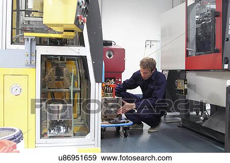 Stock Photo - Male engineer repairing manufacturing machine in factory. Fotosearch