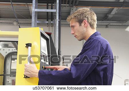 Stock Image - Male engineer testing machine control panel in factory. Fotosearch