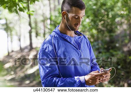 Stock Photo - Male jogger using mp3 in forest. Fotosearch