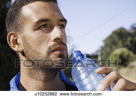 Stock Image - Man holding up water bottle. Fotosearch