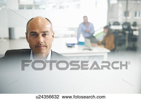 Stock Image - Man looking at camera, couple in background. Fotosearch
