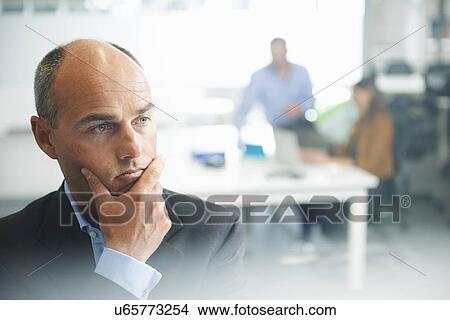 Man thinking, people in background View Large Photo Image Picture - Man thinking, people in background. Fotosearch