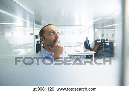 Stock Image - Man thinking, people in background. Fotosearch