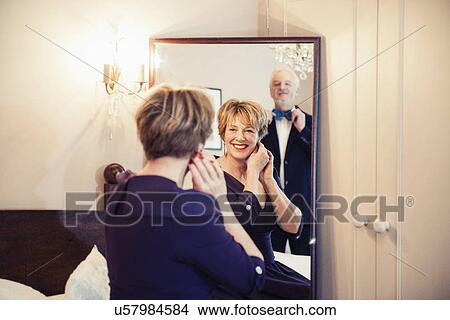 Picture - Mature woman getting ready looking in mirror. Fotosearch