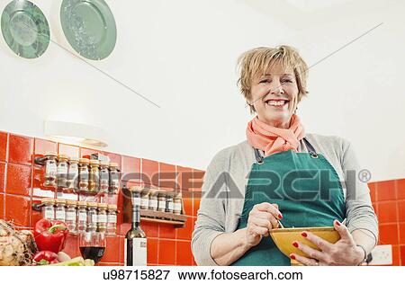 Mature woman holding mixing bowl in kitchen View Large Photo Image Stock Photo - Mature woman holding mixing bowl in kitchen. Fotosearch