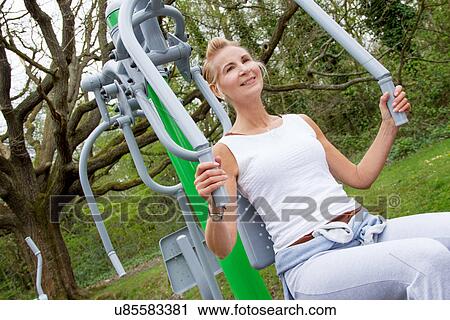 Mature woman using exercise machine in park View Large Photo Image Stock Image - Mature woman using exercise machine in park. Fotosearch