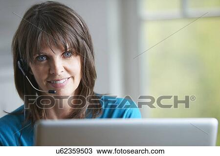 Mature woman using laptop and telephone headset View Large Photo Image Stock Image - Mature woman using laptop and telephone headset. Fotosearch