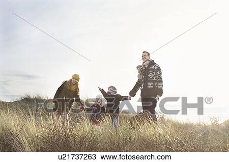Stock Image - Mid adult couple standing in sand dunes with their son, daughter and dog. Fotosearch