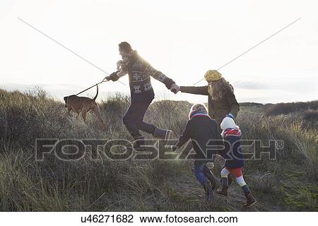 Mid adult couple strolling in sand dunes with their son, daughter and dog View Large Photo Image Stock Image - Mid adult couple strolling in sand dunes with their son, daughter and dog. Fotosearch