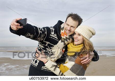 Mid adult couple taking selfie with smartphone on beach, Bloemendaal aan Zee, Netherlands View Large Photo Image Stock Image - Mid adult couple taking selfie with smartphone on beach, Bloemendaal aan Zee, Netherlands. Fotosearch