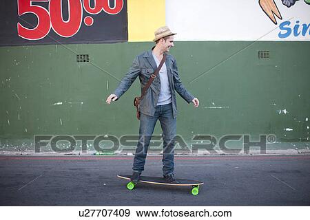 Mid adult male skateboarding on city street View Large Photo Image Stock Photo - Mid adult male skateboarding on city street. Fotosearch