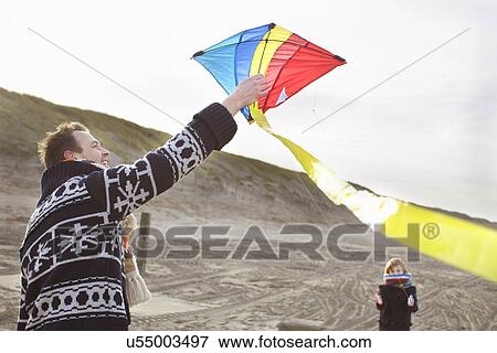 Mid adult man and son preparing to fly kite on beach, Bloemendaal aan Zee, Netherlands View Large Photo Image Stock Photo - Mid adult man and son preparing to fly kite on beach, Bloemendaal aan Zee, Netherlands. Fotosearch