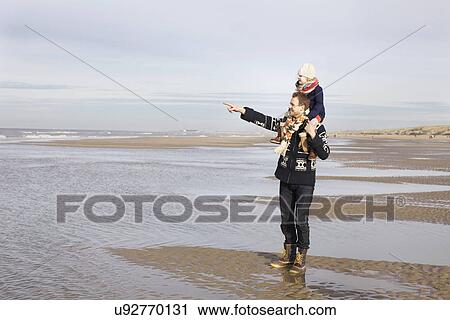 Stock Image - Mid adult man giving daughter shoulder ride on beach, Bloemendaal aan Zee, Netherlands. Fotosearch
