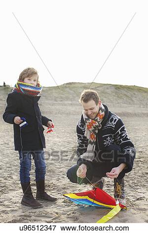 Mid adult man preparing kite for son on beach, Bloemendaal aan Zee, Netherlands View Large Photo Image Stock Photo - Mid adult man preparing kite for son on beach, Bloemendaal aan Zee, Netherlands. Fotosearch