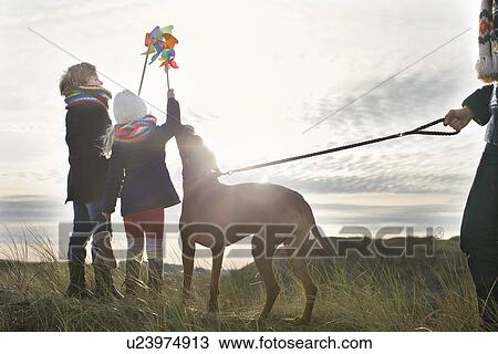 Stock Image - Mid adult man with son, daughter and dog at coast. Fotosearch