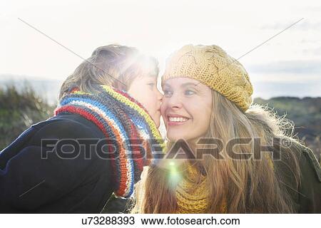 Mid adult woman with son kissing her cheek at coast View Large Photo Image Stock Image - Mid adult woman with son kissing her cheek at coast. Fotosearch