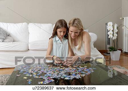 Mother and daughter doing jigsaw puzzle on coffee table View Large Photo Image Stock Photo - Mother and daughter doing jigsaw puzzle on coffee table. Fotosearch