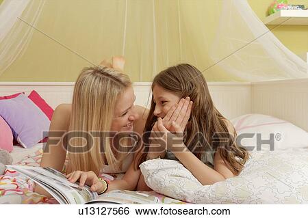 Mother and daughter lying on bed browsing magazine View Large Photo Image Stock Photograph - Mother and daughter lying on bed browsing magazine. Fotosearch