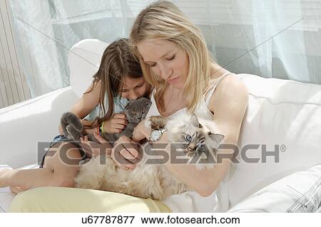 Mother and daughter on sofa hugging cats View Large Photo Image Stock Photo - Mother and daughter on sofa hugging cats. Fotosearch