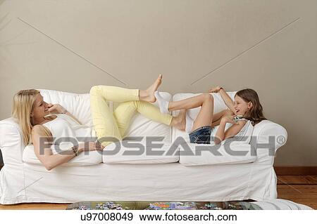 Mother and daughter playing footsie on sofa View Large Photo Image Stock Photo - Mother and daughter playing footsie on sofa. Fotosearch