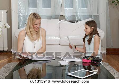 Mother and daughter reading notes in sitting room View Large Photo Image Stock Photograph - Mother and daughter reading notes in sitting room. Fotosearch