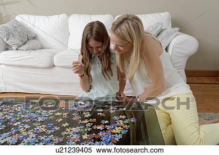 Stock Photography - Mother helping daughter do jigsaw puzzle. Fotosearch