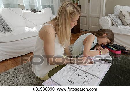 Mother helping daughter with homework on coffee table View Large Photo Image Stock Image - Mother helping daughter with homework on coffee table. Fotosearch