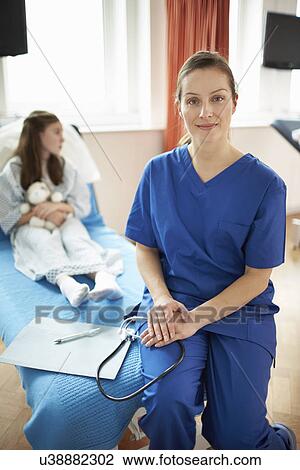 Stock Image - Nurse sitting on end of patient's bed. Fotosearch