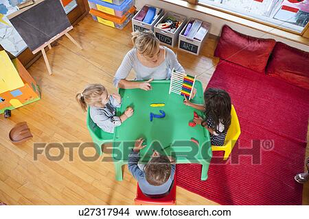 Picture - Overhead view of teacher and pupils counting at nursery school. Fotosearch