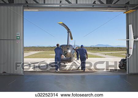 Pilots pushing helicopter onto tarmac View Large Photo Image Picture - Pilots pushing helicopter onto tarmac. Fotosearch