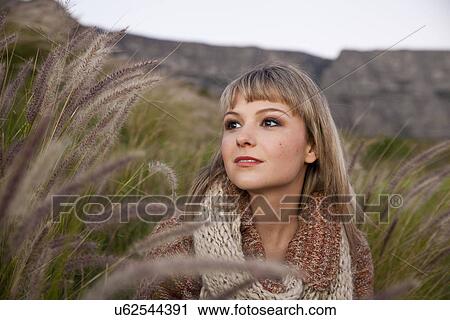 Stock Image - Portrait of beautiful young woman gazing from marsh grasses. Fotosearch