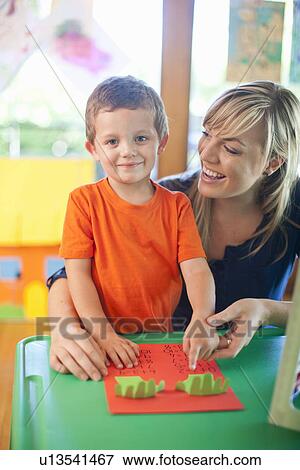 Stock Photo - Portrait of boy and teacher counting at nursery school. Fotosearch