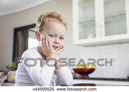 Stock Photography - Portrait of cheeky four year old boy in kitchen. Fotosearch