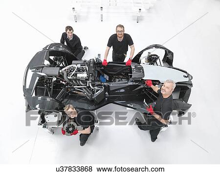 Stock Photo - Portrait of engineers assembling supercar in sports car factory, overhead view. Fotosearch