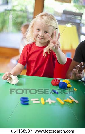 Stock Photo - Portrait of girl counting with fingers at nursery school. Fotosearch