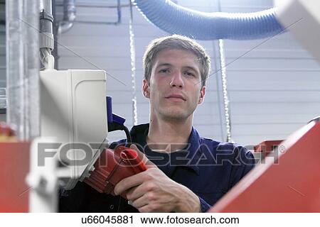 Stock Image - Portrait of male electrician and power supply cable in factory. Fotosearch