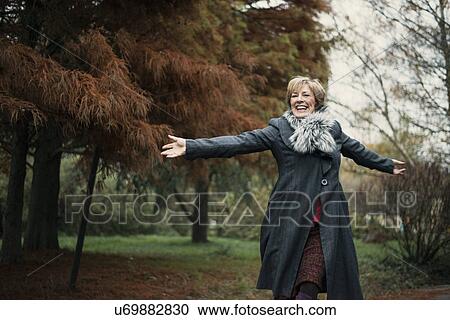Stock Image - Portrait of mature woman, arms outstretched. Fotosearch
