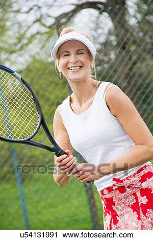 Stock Image - Portrait of mature woman playing tennis. Fotosearch
