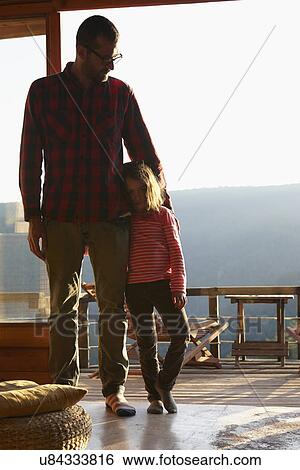 Stock Photograph - Portrait of mid adult father and daughter in sitting room. Fotosearch