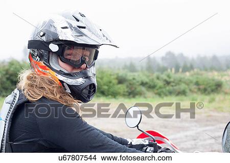 Portrait of mid adult female motorcyclist in crash helmet and goggles View Large Photo Image Picture - Portrait of mid adult female motorcyclist in crash helmet and goggles. Fotosearch