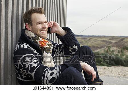 Portrait of mid adult man chatting on smartphone at coast View Large Photo Image Stock Image - Portrait of mid adult man chatting on smartphone at coast. Fotosearch