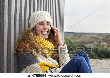 Portrait of mid adult woman chatting on smartphone at coast View Large Photo Image Picture - Portrait of mid adult woman chatting on smartphone at coast. Fotosearch