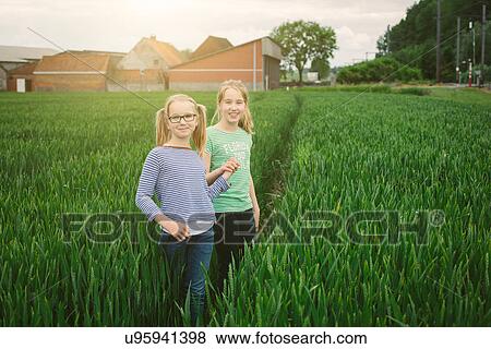Stock Photo - Portrait of nine year old girl and sister on field path. Fotosearch