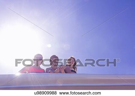 Stock Photo - Portrait of three adult friends looking down from yacht. Fotosearch