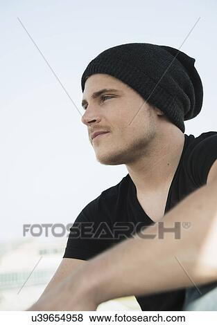 Stock Photo - Portrait of young man wearing black tshirt and knit hat. Fotosearch