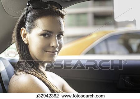 Stock Image - Portrait of young woman in taxi. Fotosearch