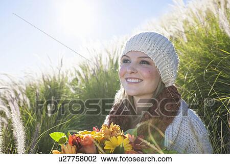 Portrait of young woman with bunch of flowers in long grass View Large Photo Image Stock Image - Portrait of young woman with bunch of flowers in long grass. Fotosearch