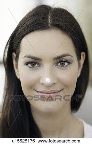 Stock Photograph - Portrait of young woman with dab of cream on her nose. Fotosearch