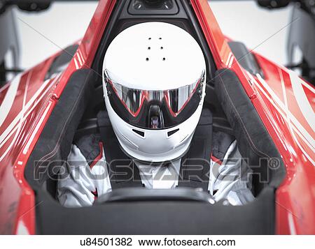 Stock Image - Racing driver wearing crash helmet in supercar. Fotosearch